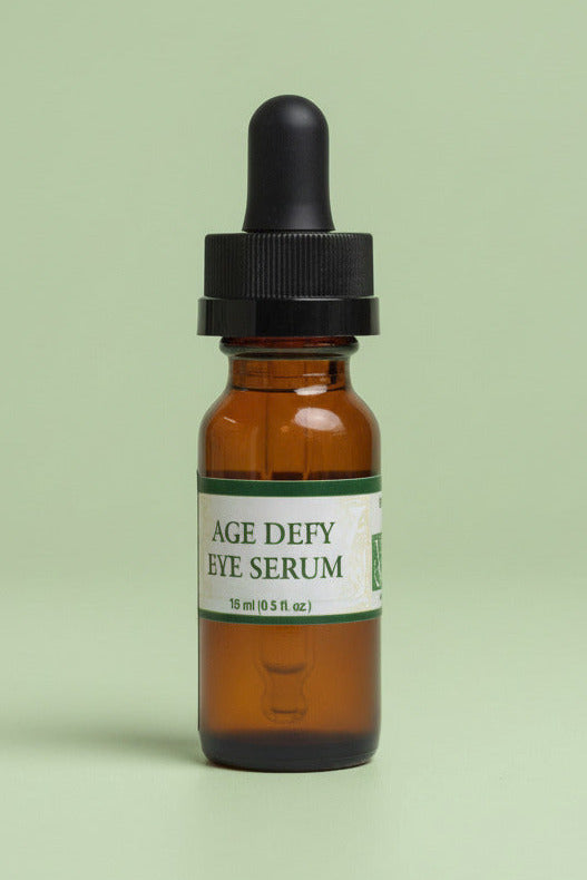 Brown glass dropper bottle labeled 'AGE DEFY EYE SERUM' on a light green background
